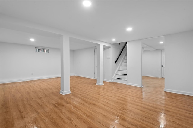 finished below grade area featuring recessed lighting, stairway, light wood-type flooring, and baseboards