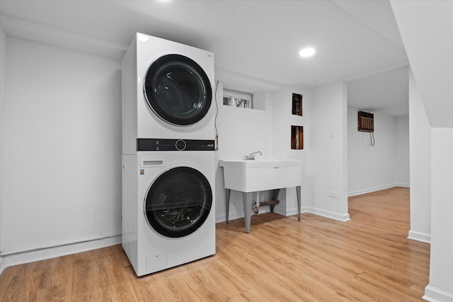 laundry room featuring stacked washing maching and dryer, baseboards, laundry area, and wood finished floors