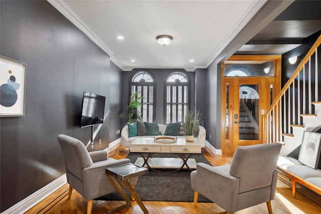 living area with crown molding, stairway, baseboards, and wood finished floors