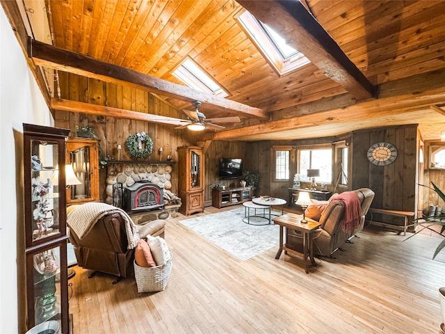 living room with vaulted ceiling with skylight, wooden walls, and wood finished floors