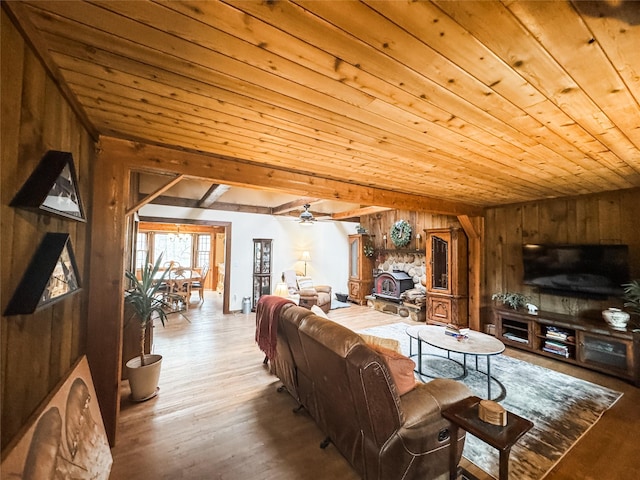 living room featuring a ceiling fan, wood ceiling, wooden walls, and wood finished floors