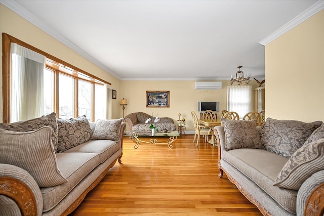 living area featuring light wood finished floors, a wall mounted air conditioner, an inviting chandelier, and crown molding