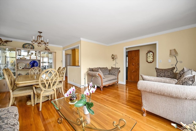 living room with a chandelier, light wood-type flooring, and ornamental molding