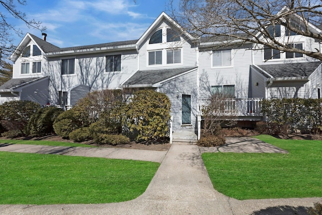 view of property with a front lawn and a shingled roof