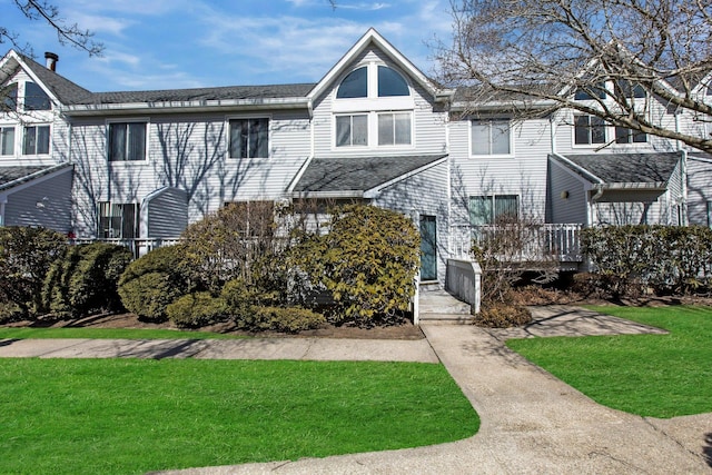 multi unit property with a front yard and roof with shingles