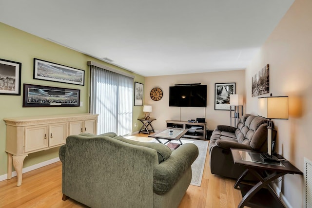 living room with light wood-style flooring, visible vents, and baseboards