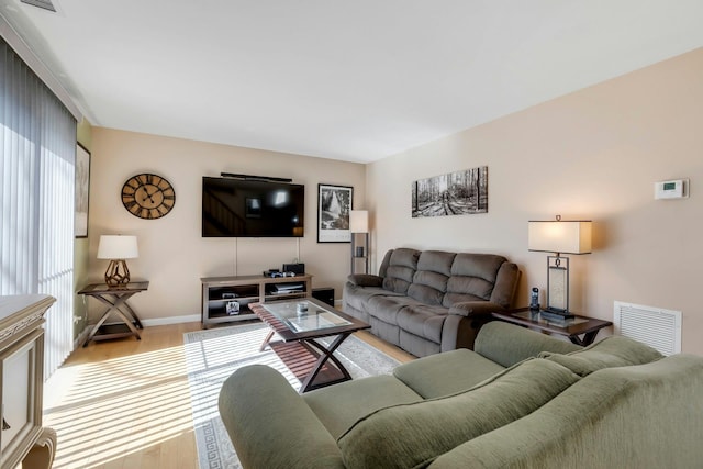 living area with baseboards, visible vents, and light wood finished floors