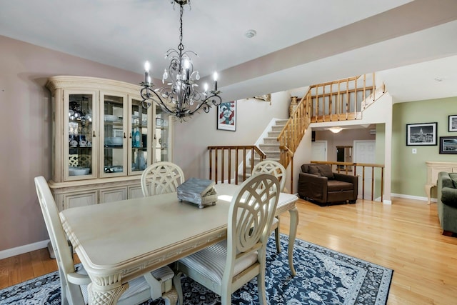 dining space featuring light wood finished floors, stairs, and baseboards