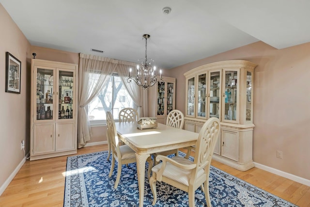 dining space featuring visible vents, a notable chandelier, light wood-style flooring, and baseboards