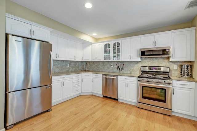 kitchen with light stone counters, stainless steel appliances, a sink, visible vents, and light wood-type flooring