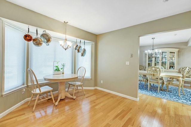 dining room with plenty of natural light, a notable chandelier, light wood-style flooring, and baseboards