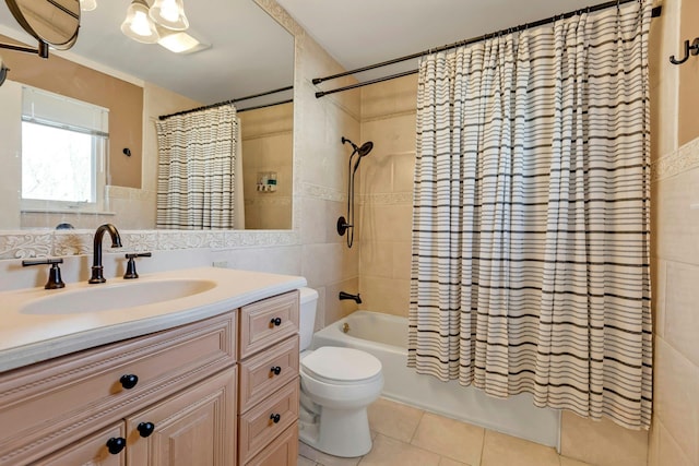 full bath featuring toilet, tile patterned floors, shower / bathtub combination with curtain, vanity, and tile walls