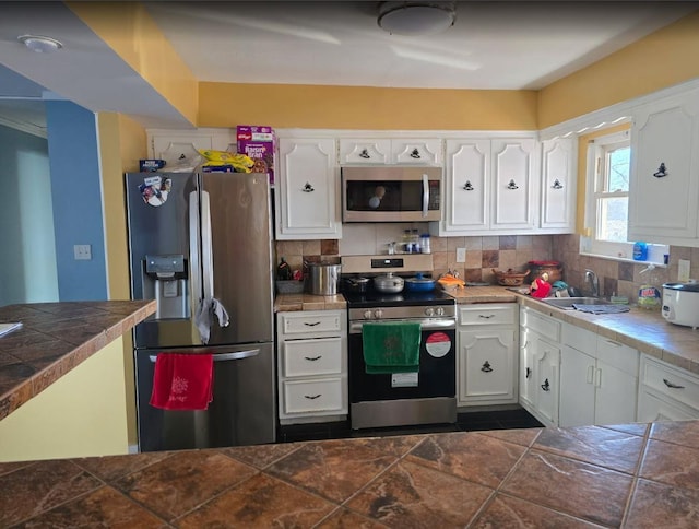 kitchen with white cabinetry, appliances with stainless steel finishes, backsplash, and a sink