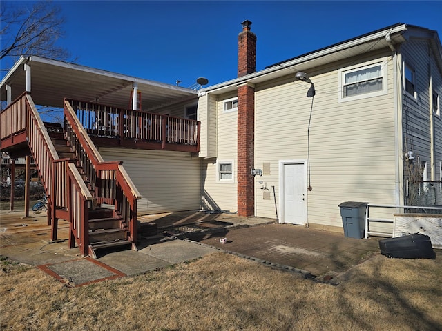 rear view of house featuring a wooden deck, a chimney, stairway, and a patio