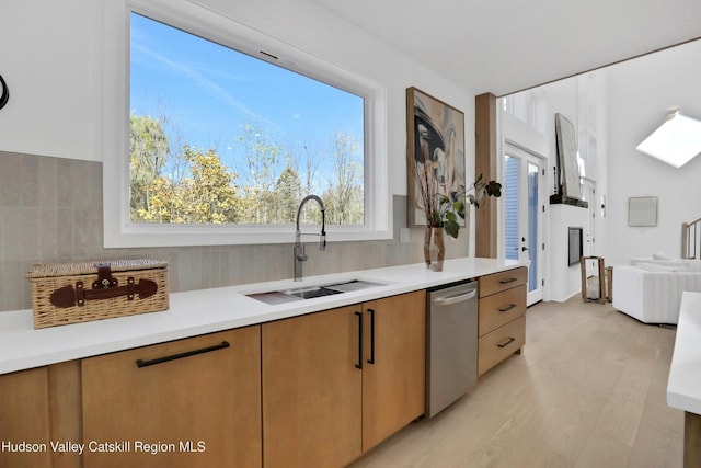 kitchen featuring light countertops, stainless steel dishwasher, a sink, and tasteful backsplash