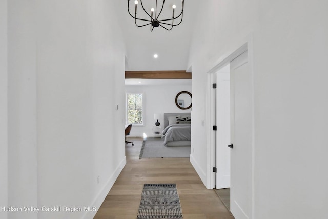 corridor with recessed lighting, wood finished floors, an inviting chandelier, and baseboards