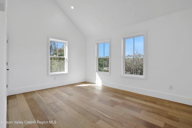 unfurnished room featuring light wood-style floors, high vaulted ceiling, and baseboards