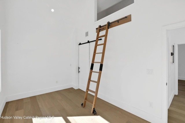 spare room featuring baseboards, a barn door, visible vents, and wood finished floors