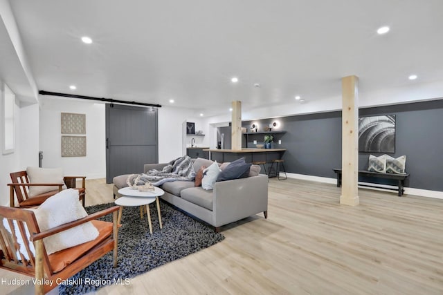 living room with baseboards, a barn door, light wood-type flooring, and recessed lighting