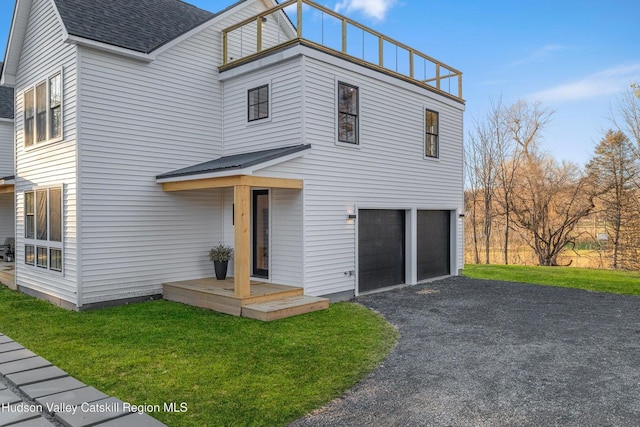 view of front of home featuring a shingled roof, a garage, a front lawn, and aphalt driveway