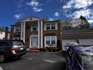 greek revival house with an attached garage and driveway