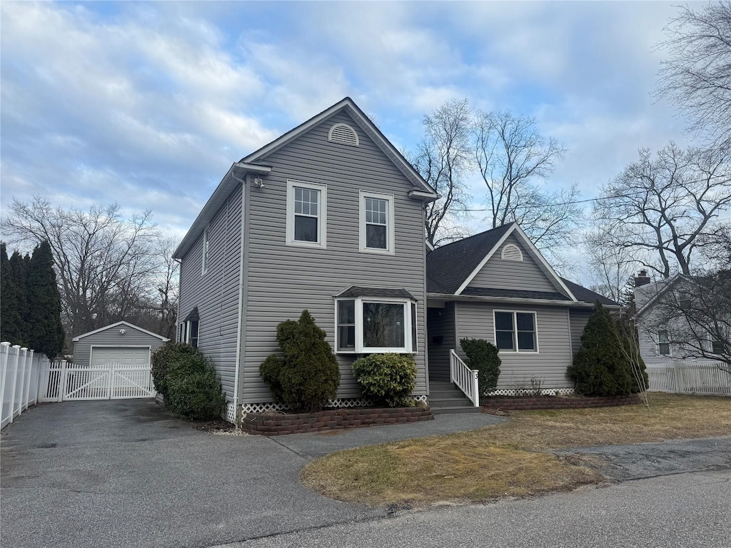 traditional home with a garage, an outdoor structure, driveway, and fence