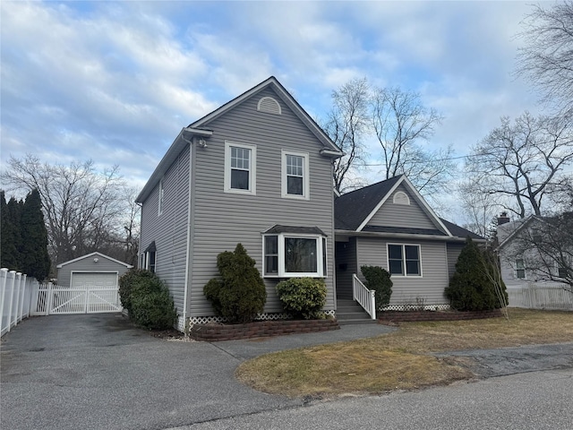 traditional home with a garage, an outdoor structure, driveway, and fence