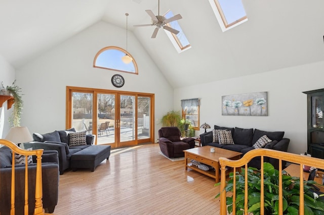 living room with high vaulted ceiling, light wood-style flooring, a ceiling fan, french doors, and a skylight