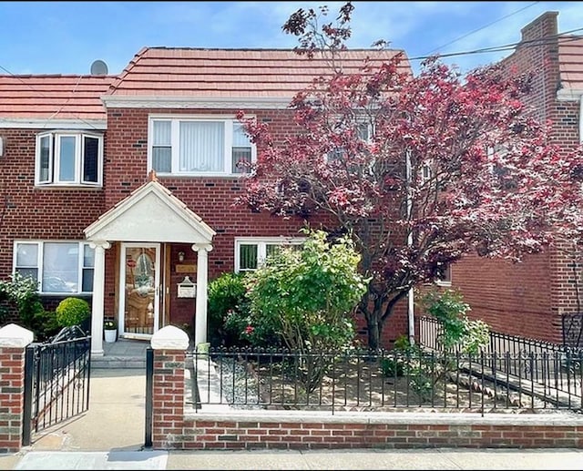 multi unit property with a fenced front yard, a gate, and brick siding