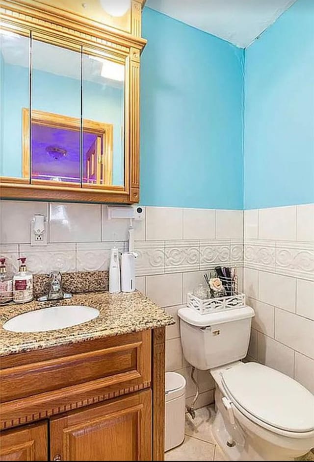 bathroom with tile patterned flooring, tile walls, vanity, and toilet