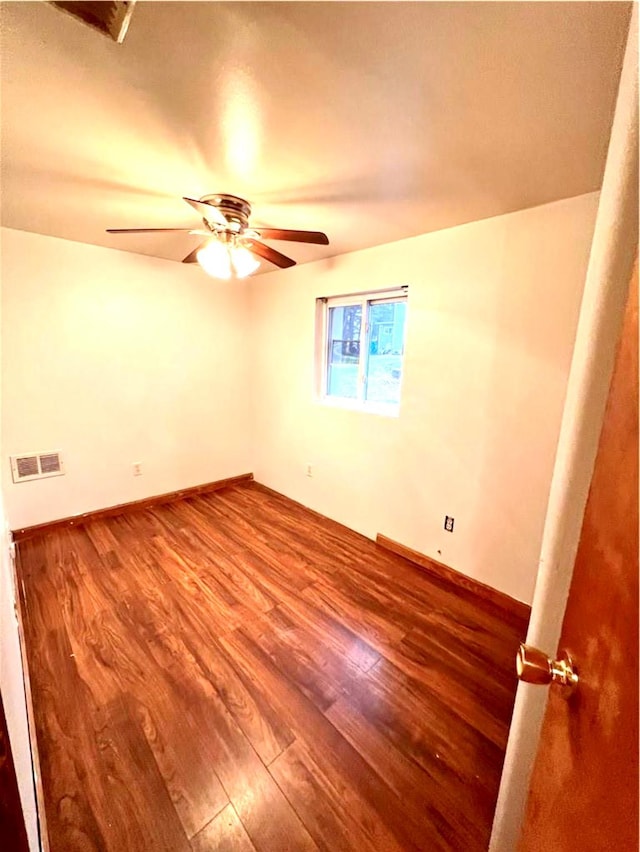 empty room featuring ceiling fan, wood finished floors, visible vents, and baseboards