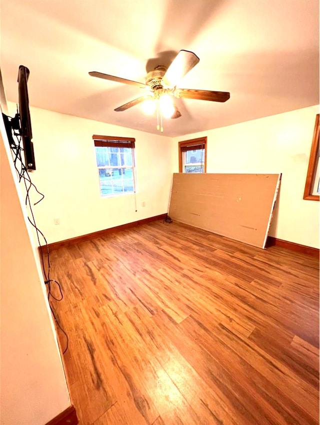 empty room featuring ceiling fan, baseboards, and wood finished floors