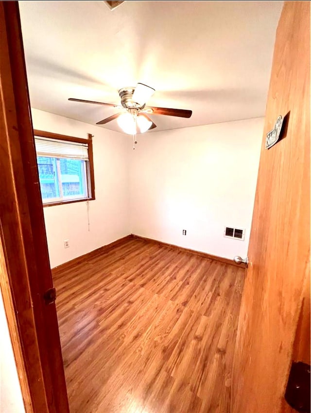 unfurnished room with wood finished floors, visible vents, and a ceiling fan