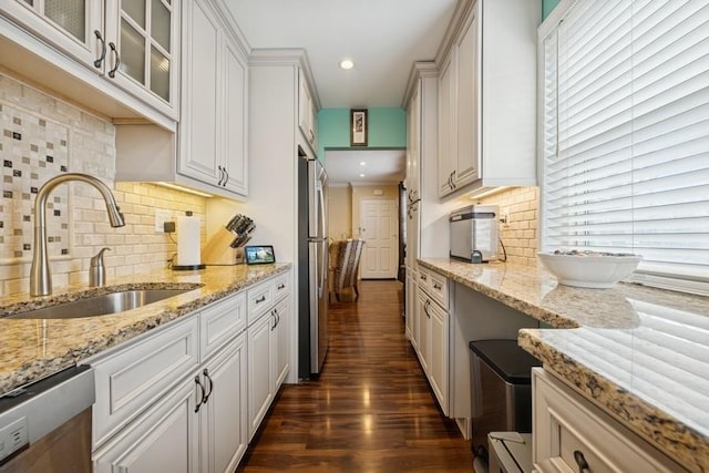 kitchen with stainless steel appliances, dark wood-type flooring, a sink, white cabinets, and glass insert cabinets