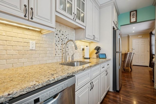 kitchen with light stone counters, dark wood-style flooring, appliances with stainless steel finishes, white cabinetry, and a sink