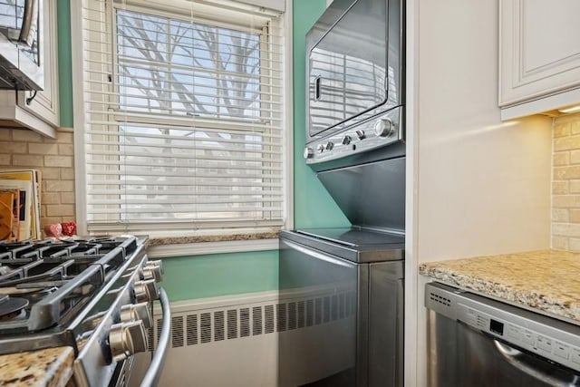 kitchen with appliances with stainless steel finishes, light stone countertops, white cabinetry, and tasteful backsplash