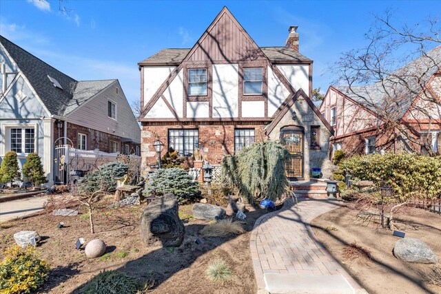 tudor home featuring brick siding and a chimney