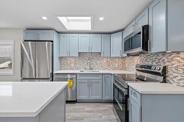 kitchen with recessed lighting, a skylight, a sink, appliances with stainless steel finishes, and tasteful backsplash