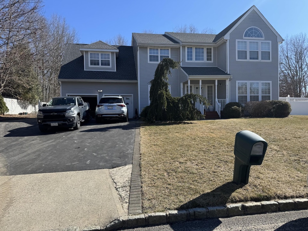 view of front of house featuring aphalt driveway, an attached garage, a front yard, and fence