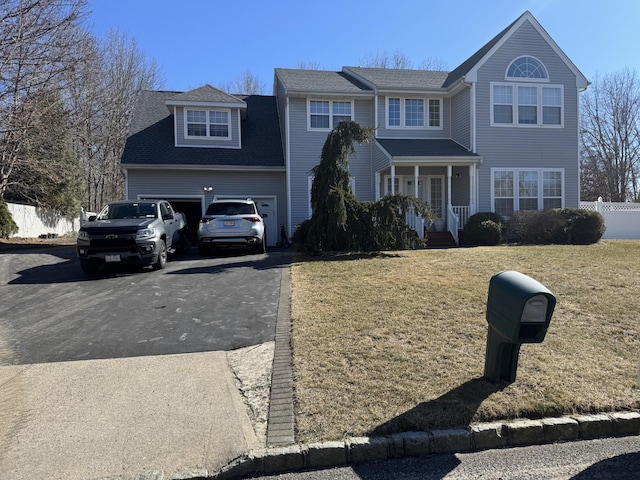 view of front of house featuring aphalt driveway, an attached garage, a front yard, and fence