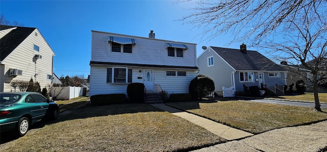 view of front of home with a front yard, fence, and a chimney