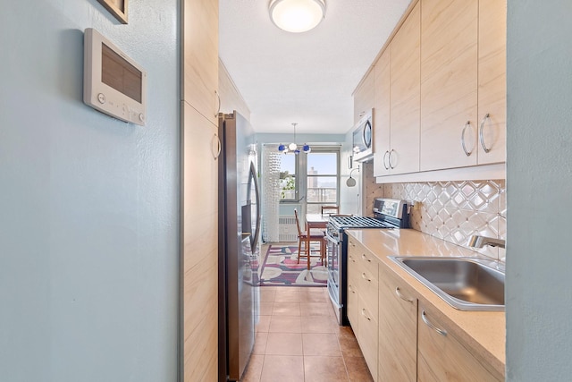 kitchen with stainless steel appliances, light countertops, decorative backsplash, a sink, and tile patterned flooring