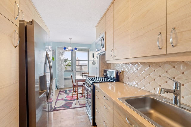 kitchen featuring tasteful backsplash, light countertops, appliances with stainless steel finishes, light tile patterned flooring, and a sink