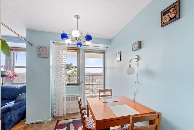 dining area with radiator heating unit, a textured ceiling, and a notable chandelier