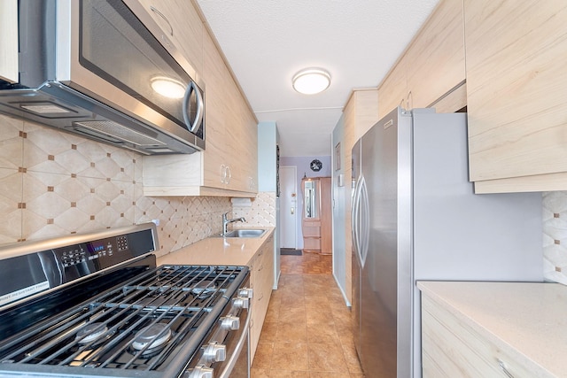 kitchen with light tile patterned floors, tasteful backsplash, appliances with stainless steel finishes, light countertops, and a sink