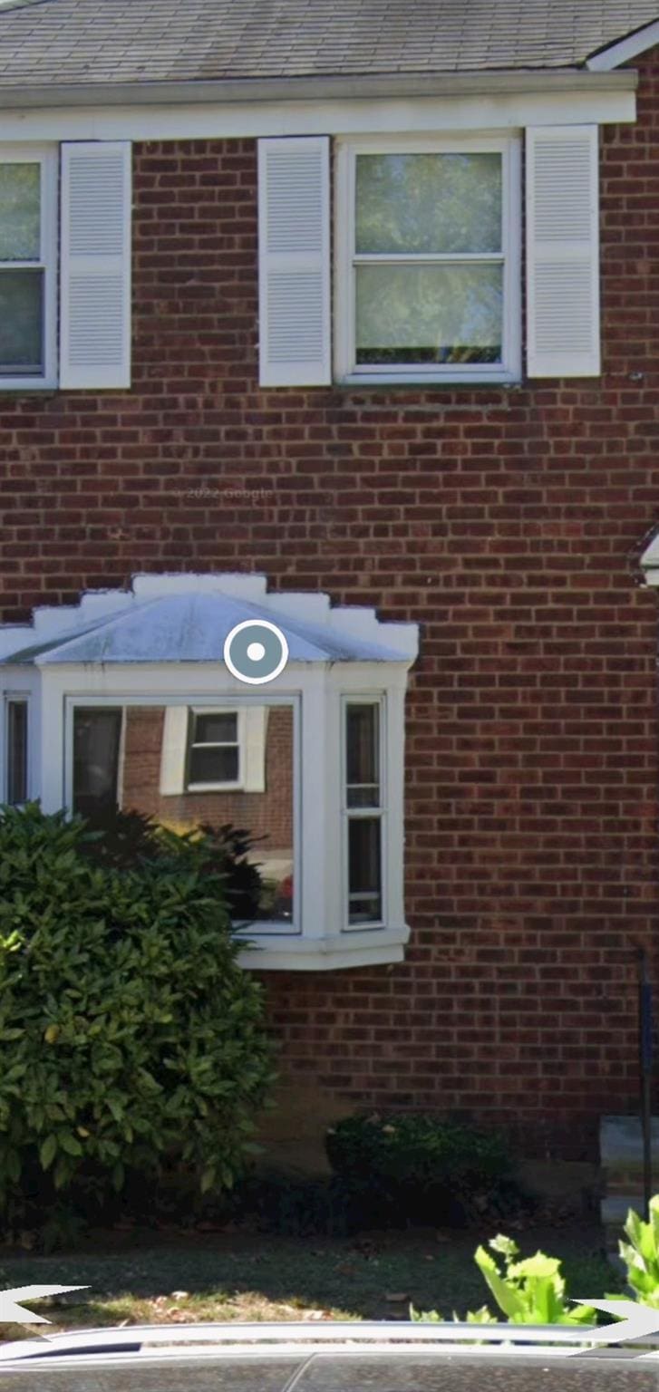 exterior space with brick siding and roof with shingles