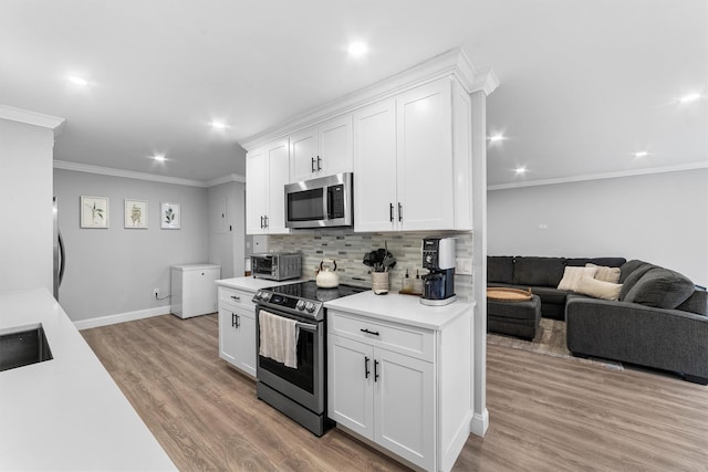 kitchen with light wood-style floors, crown molding, light countertops, appliances with stainless steel finishes, and tasteful backsplash