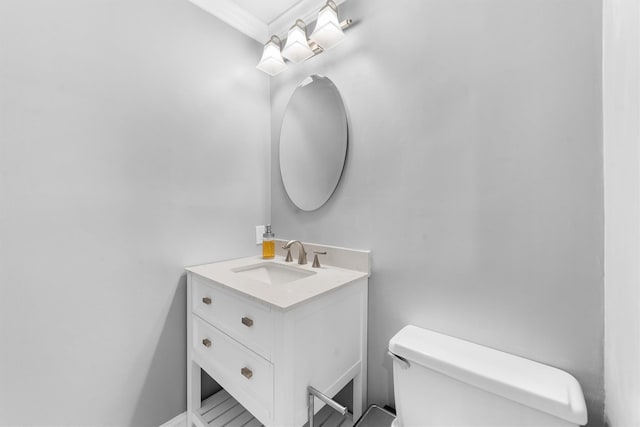 half bath featuring toilet, vanity, and ornamental molding