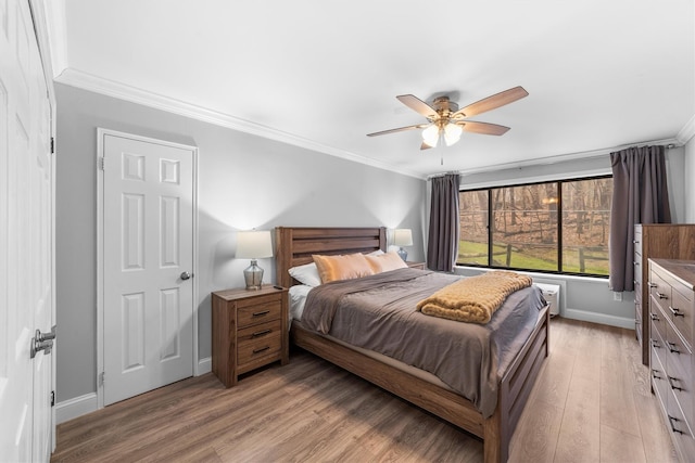 bedroom featuring ceiling fan, light wood-style floors, baseboards, and ornamental molding