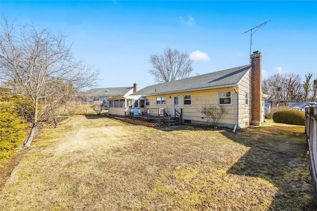 rear view of property with a deck, a chimney, and a yard